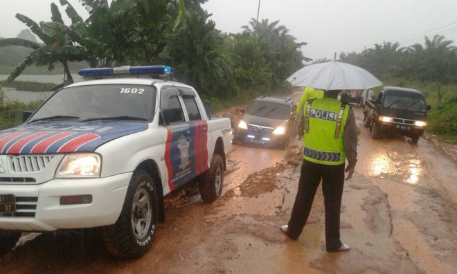 Polisi saat membantu mobil melewati jalan rusak di kumpe ilir